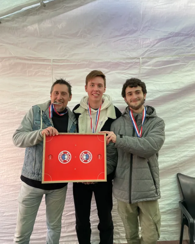 Tres jugadores con medallas y un tablero rojo