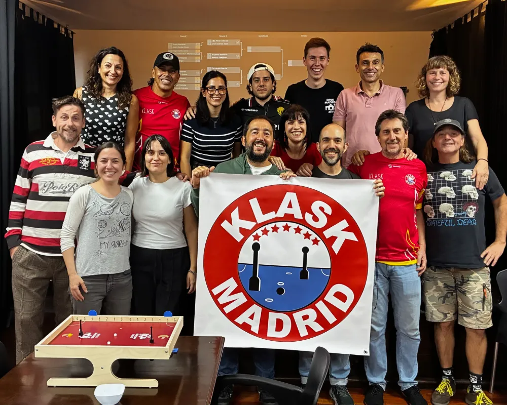 Grupo de jugadores con la bandera de KlaskMadrid y un tablero